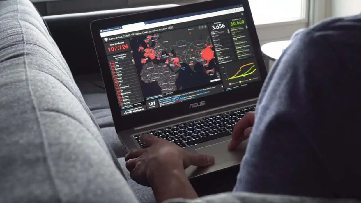 Using laptop with world map of coronavirus